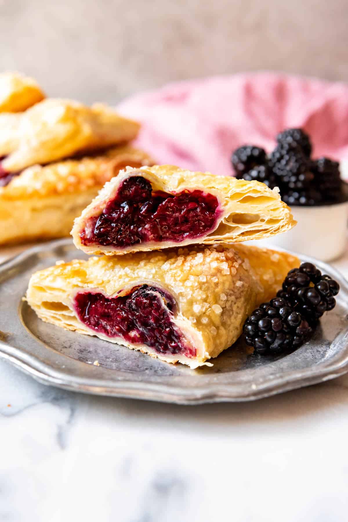 A blackberry turnover that has been cut in half on a plate.