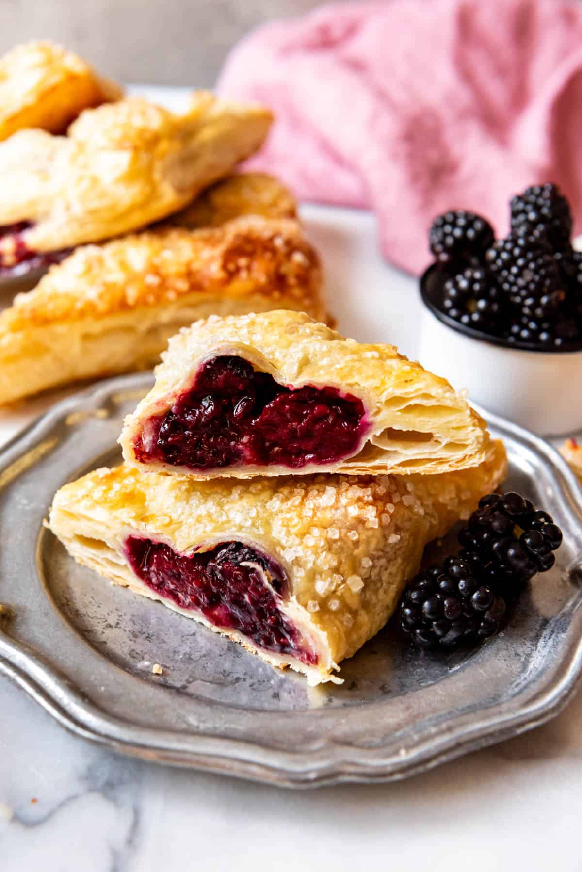 An image of a blackberry hand pie or turnover cut in half on a plate.