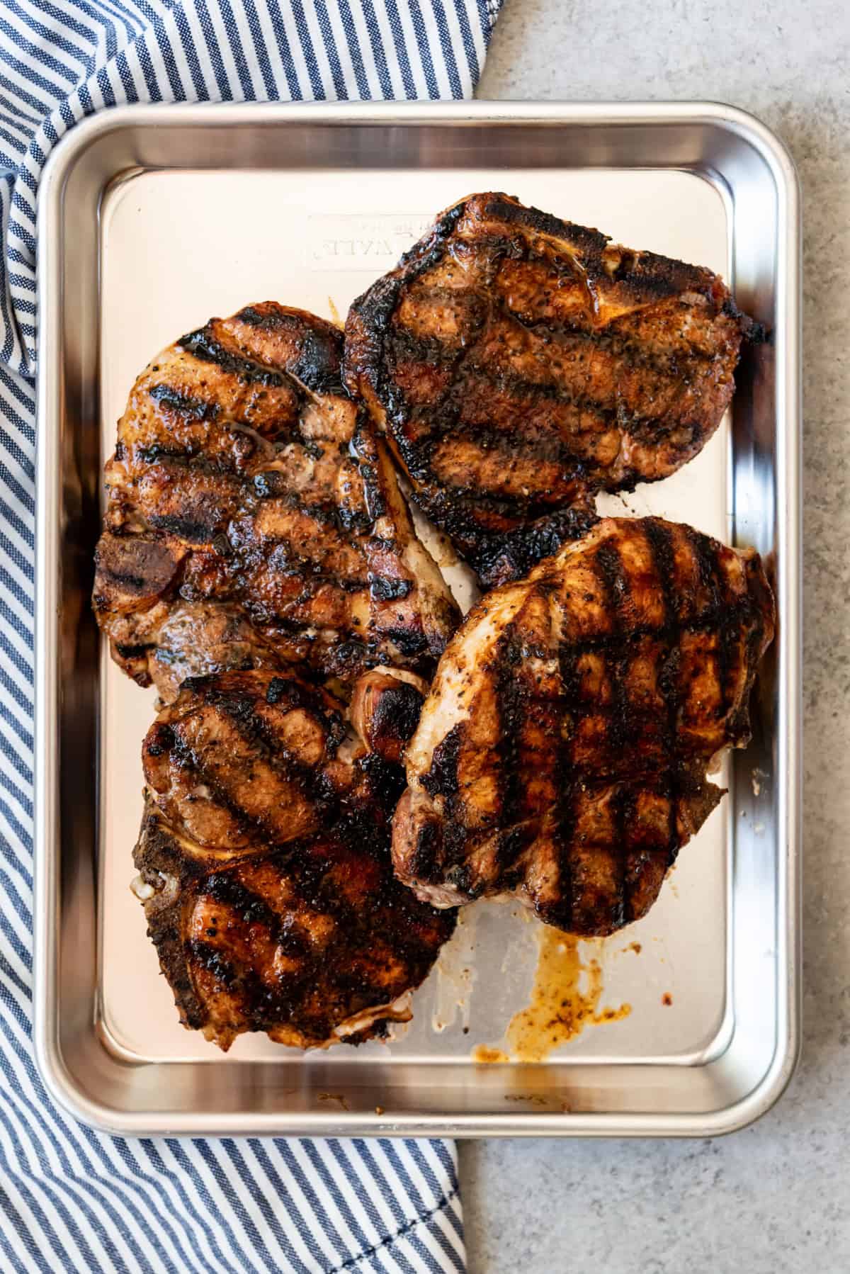 An image of four grilled bone-in grilled pork chops with grill marks.