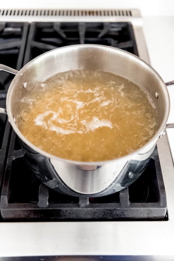 An image of a pot of boiling water with macaroni noodles on the stove.