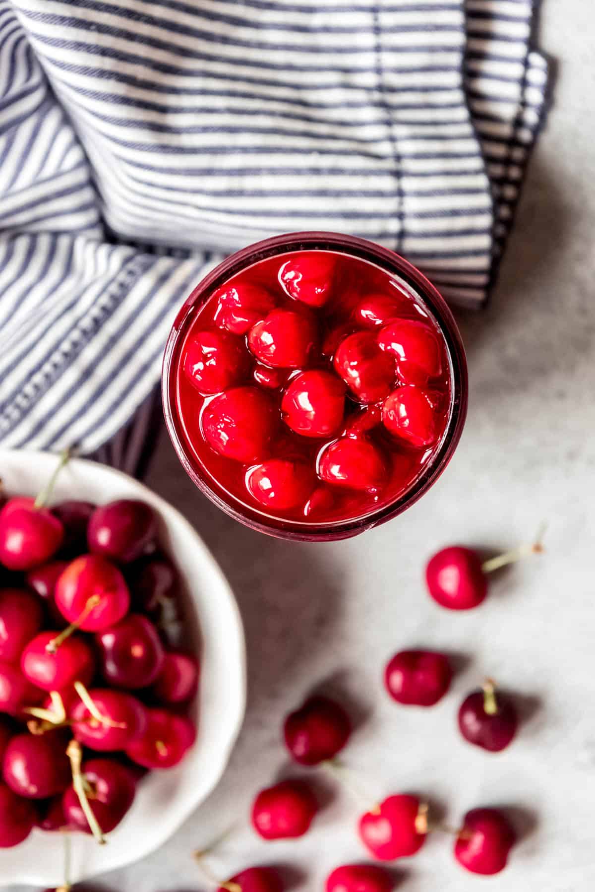 Fresh cherry pie filling next to a bowl of cherries.