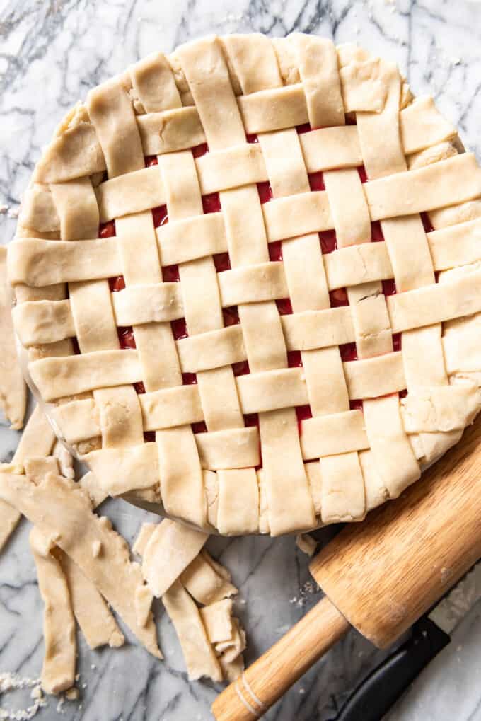 Tucking the ends of lattice pie crust strips under to finish a cherry pie before baking.
