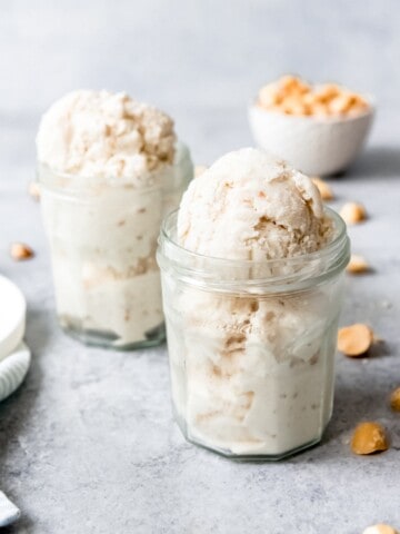 An image of two glass jars filled with scoops of homemade coconut macadamia nut ice cream.