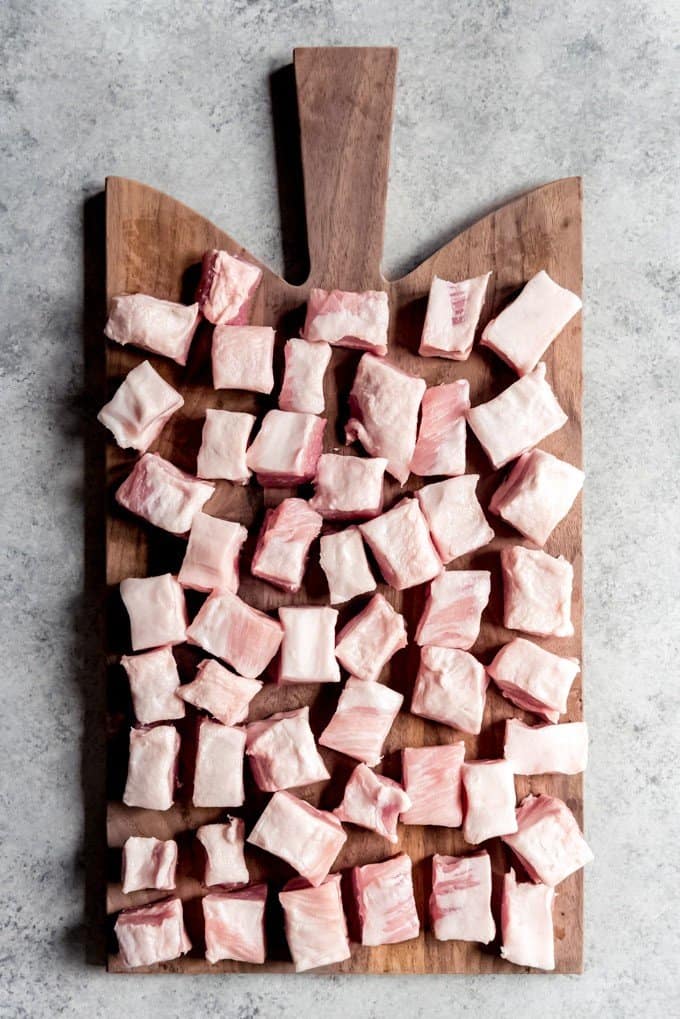 An image of cubes of pork belly on a cutting board.