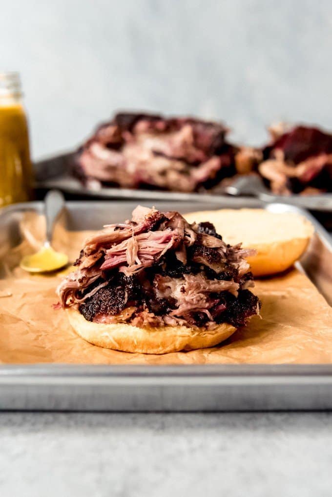 An image of smoked pulled pork piled on a bun to make a sandwich.