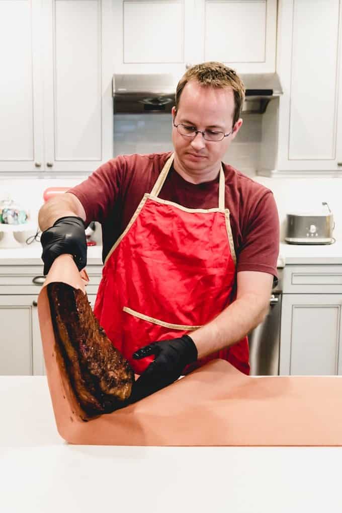 An image of a Texas smoked brisket being wrapped in butcher paper for a Texas crutch method of getting through the stall.