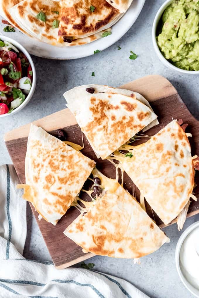 An image of a cheesy chicken quesadilla cut into triangles and being pulled apart with cheese stretching between each triangle.