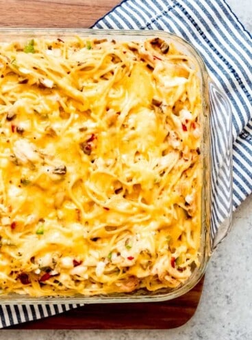 An image of a homemade Chicken Spaghetti Casserole topped with melted cheddar cheese.