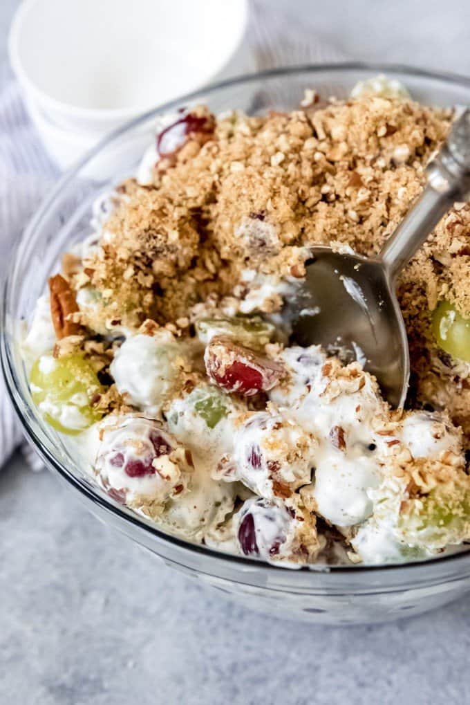 An image of a bowl of creamy grape salad with brown sugar pecan topping.