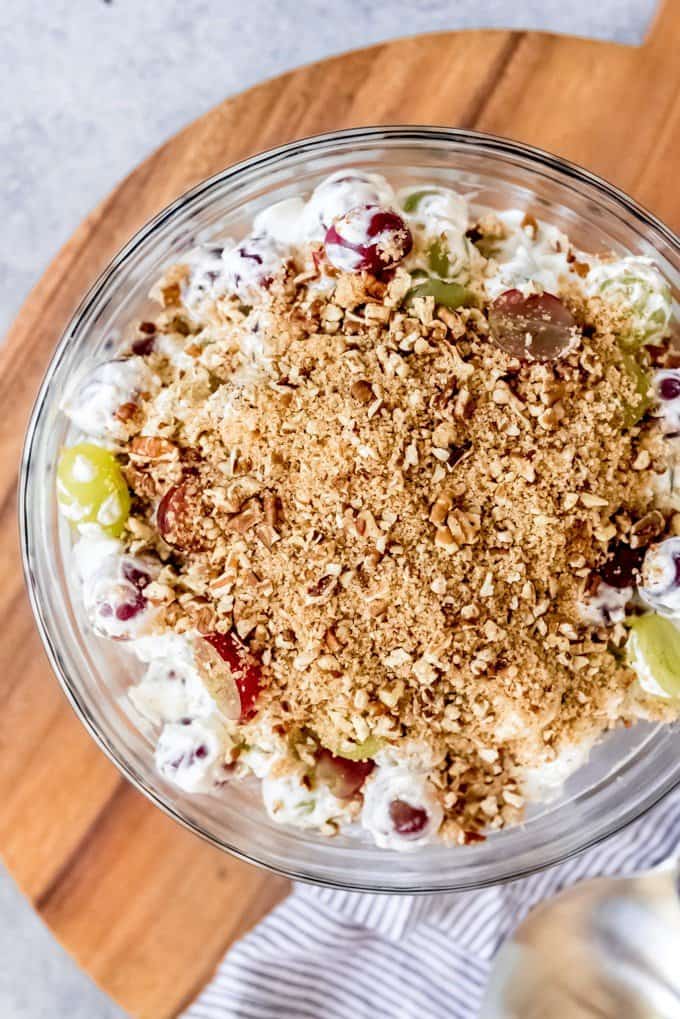 An image of a potluck favorite - creamy grape salad with crunch pecan brown sugar topping.
