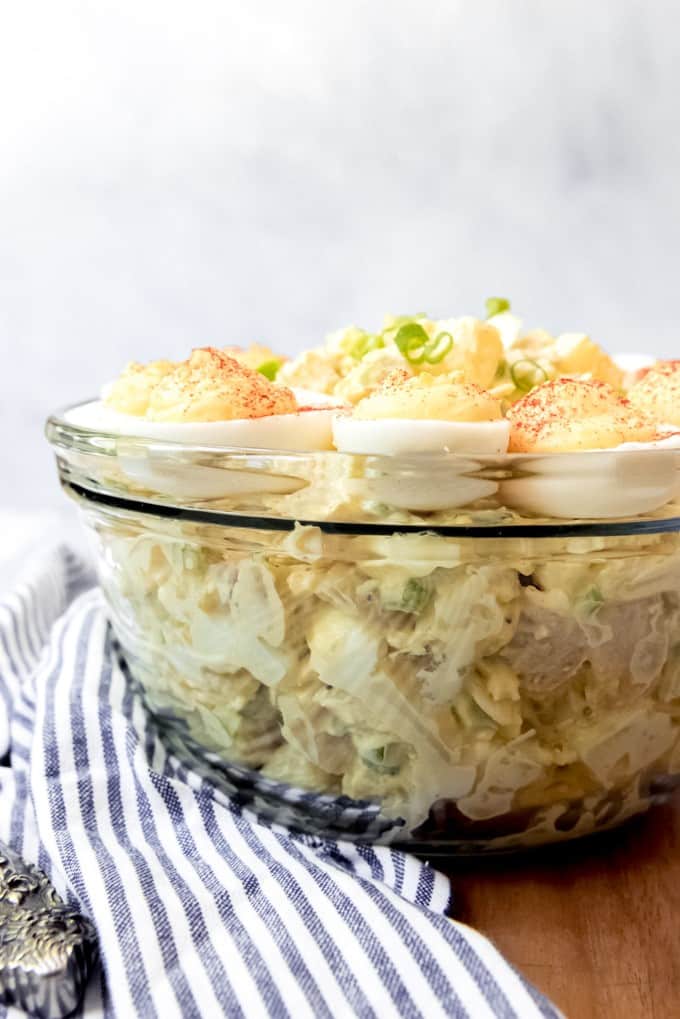 An image of a glass bowl filled with classic potato salad topped with the best deviled eggs.