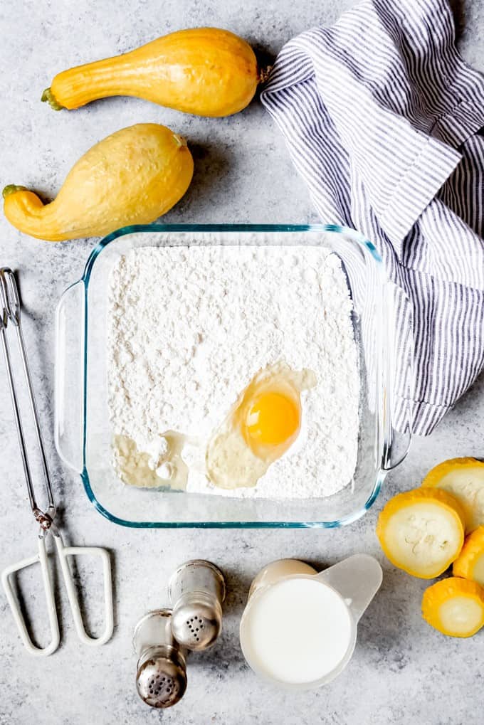 An image of flour and an egg in a shallow dish for making a simple batter to fry squash from the garden.