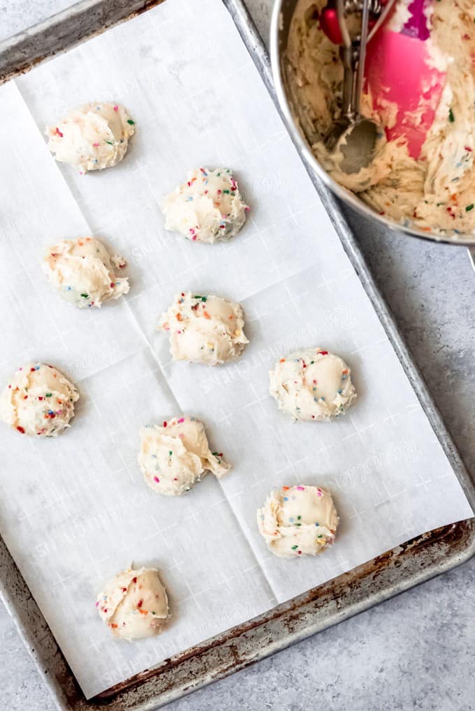 An image of funfetti cookie batter on a parchment-lined baking sheet.
