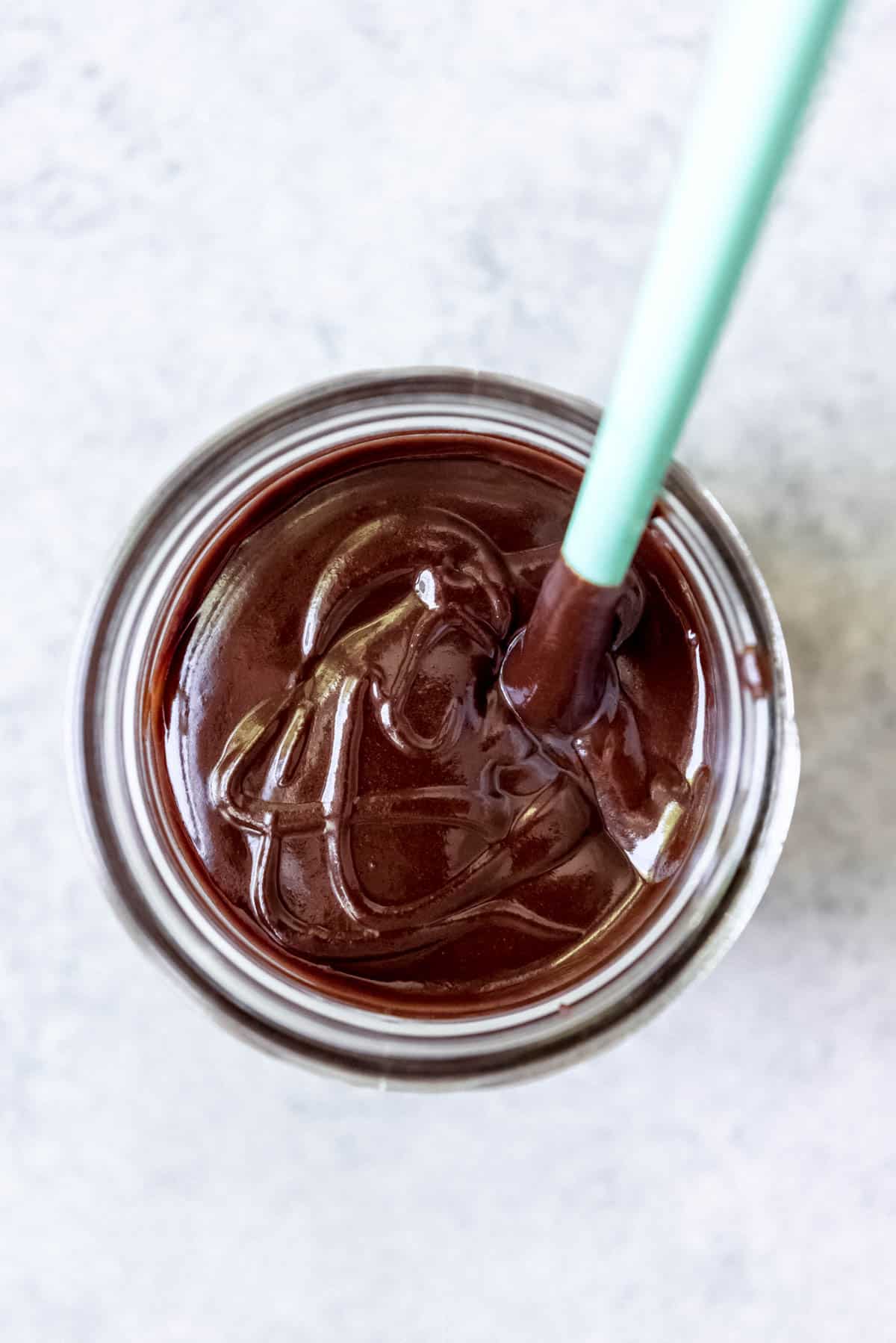 An overhead image of hot fudge sauce in a glass jar.