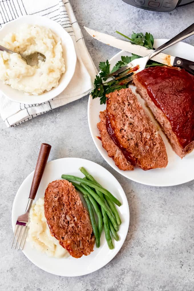 An image of a thick-sliced meatloaf with creamy mashed potatoes and green beans.