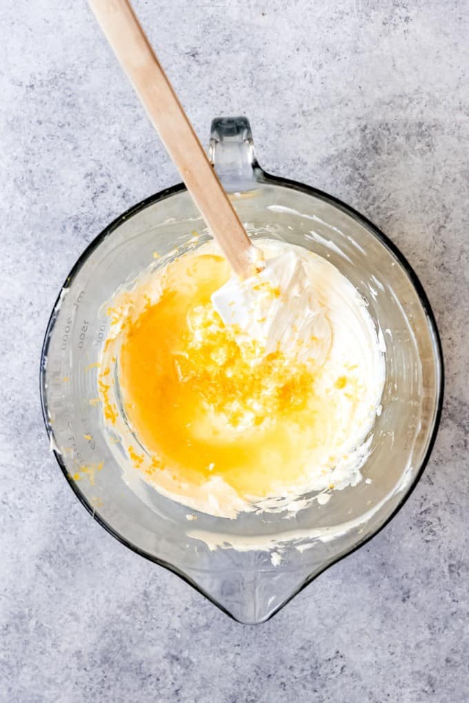 An image of lemon juice and lemon zest being added to a bowl of cream cheese filling for an icebox cake.