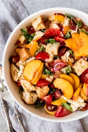 Peach Panzanella Salad is an easy summer salad recipe that is loaded with fresh flavors of heirloom tomatoes, basil leaves, mozzarella, juicy ripe peaches, and torn crusty bread with a simple honey dijon vinaigrette!  It's perfect for potlucks, picnics, light summer dinners and easy no-fuss lunches!