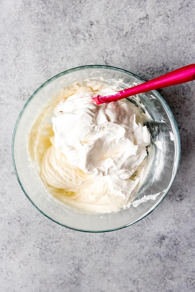 An image of Cool Whip being folded into a cream cheese and sugar mixture for the creamy layer in raspberry pretzel salad.