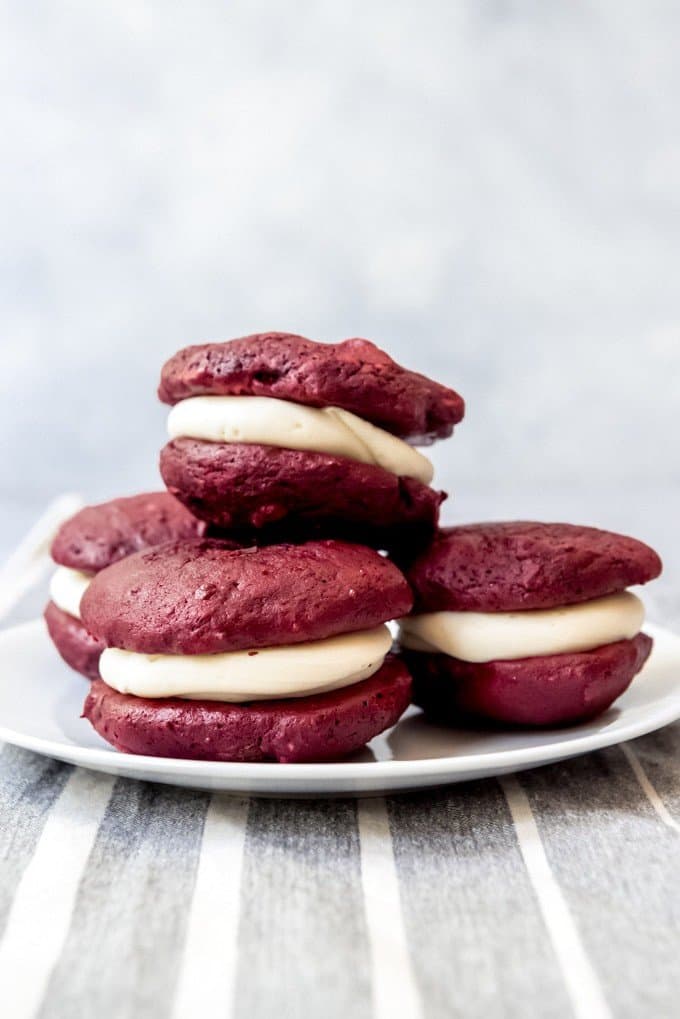 An image of homemade red velvet whoopie pies stacked on a plate.