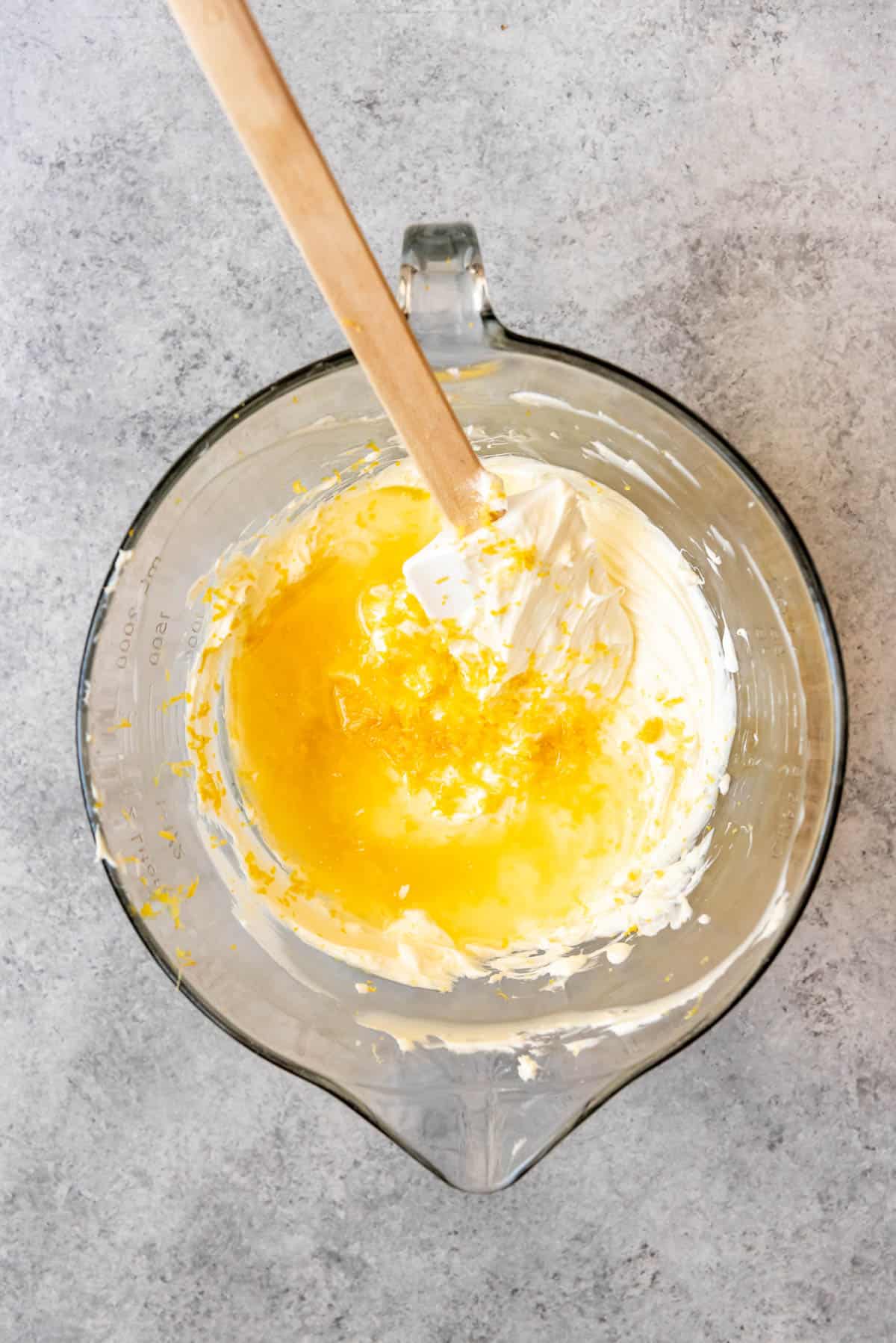 An image of lemon juice and lemon zest being added to a bowl of cream cheese filling for an icebox cake.