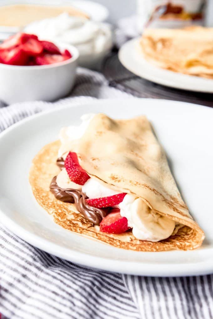 An image of a classic French crepe filled with nutella, bananas, whipped cream, and strawberries.