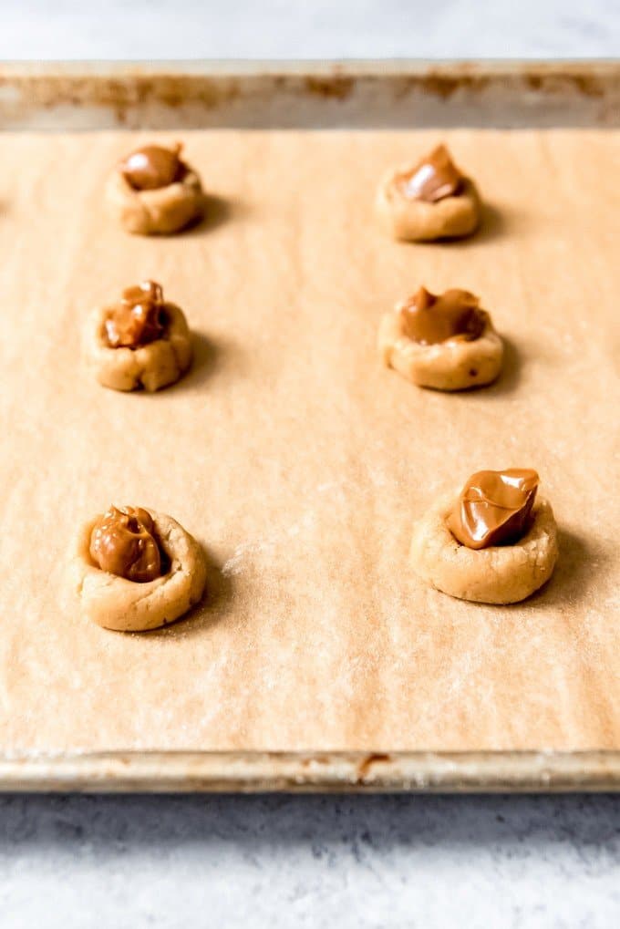 An image of balls of brown sugar cookie dough with dulce de leche spoon on top.