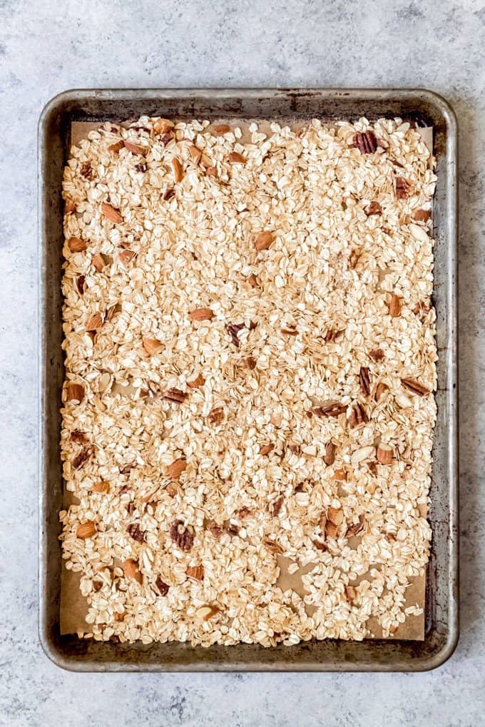 An image of a baking sheet with toasted oats and nuts for making chewy granola bars.