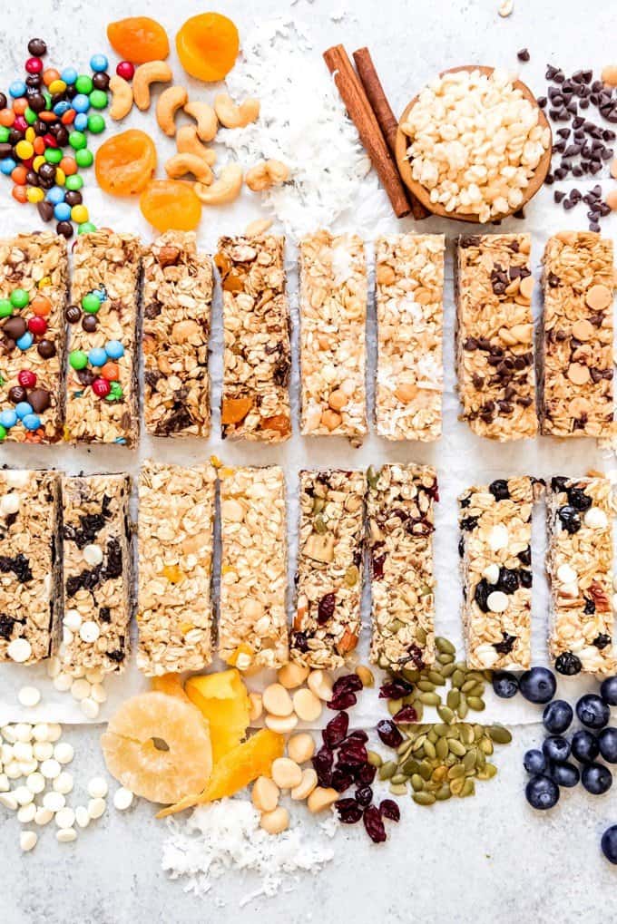 An image of 8 different flavors of homemade granola bars surrounded by granola bar ingredients.