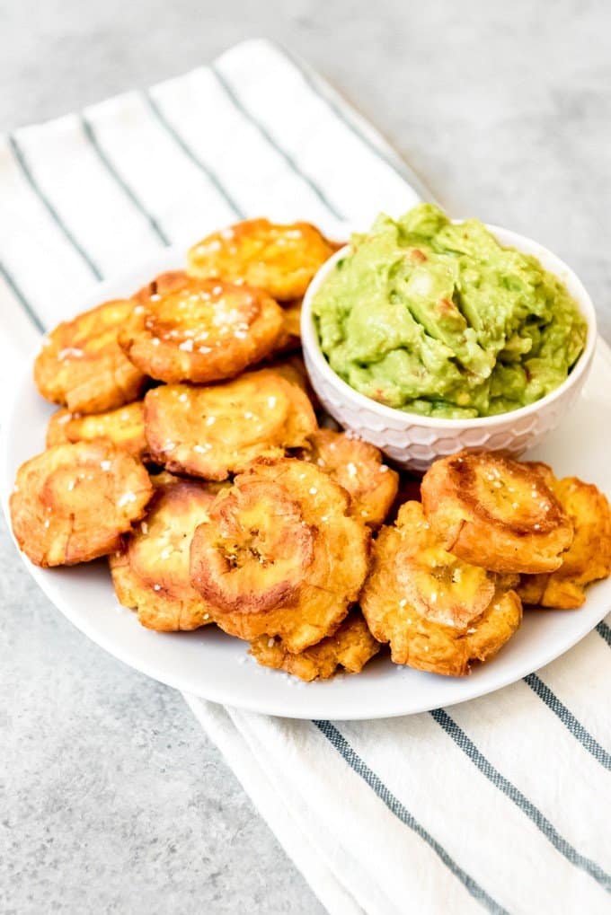 An image of a plate of fried green plantains and guacamole for snacking.