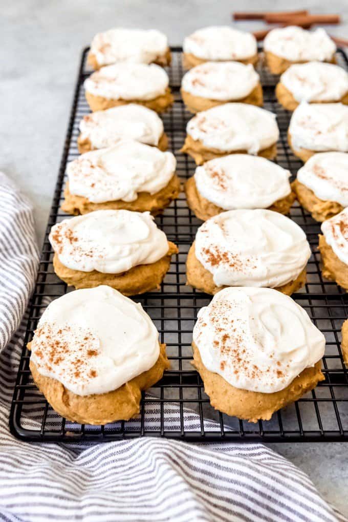 An image of frosted pumpkin cookies on a wire cooling rack.