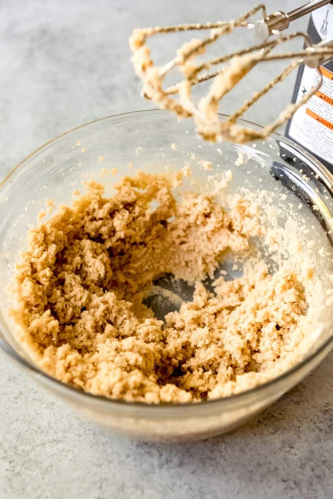 Creaming butter and sugars in a bowl with a hand mixer.