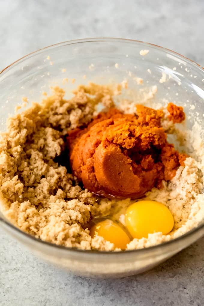 Adding pumpkin puree and eggs to cookie dough.