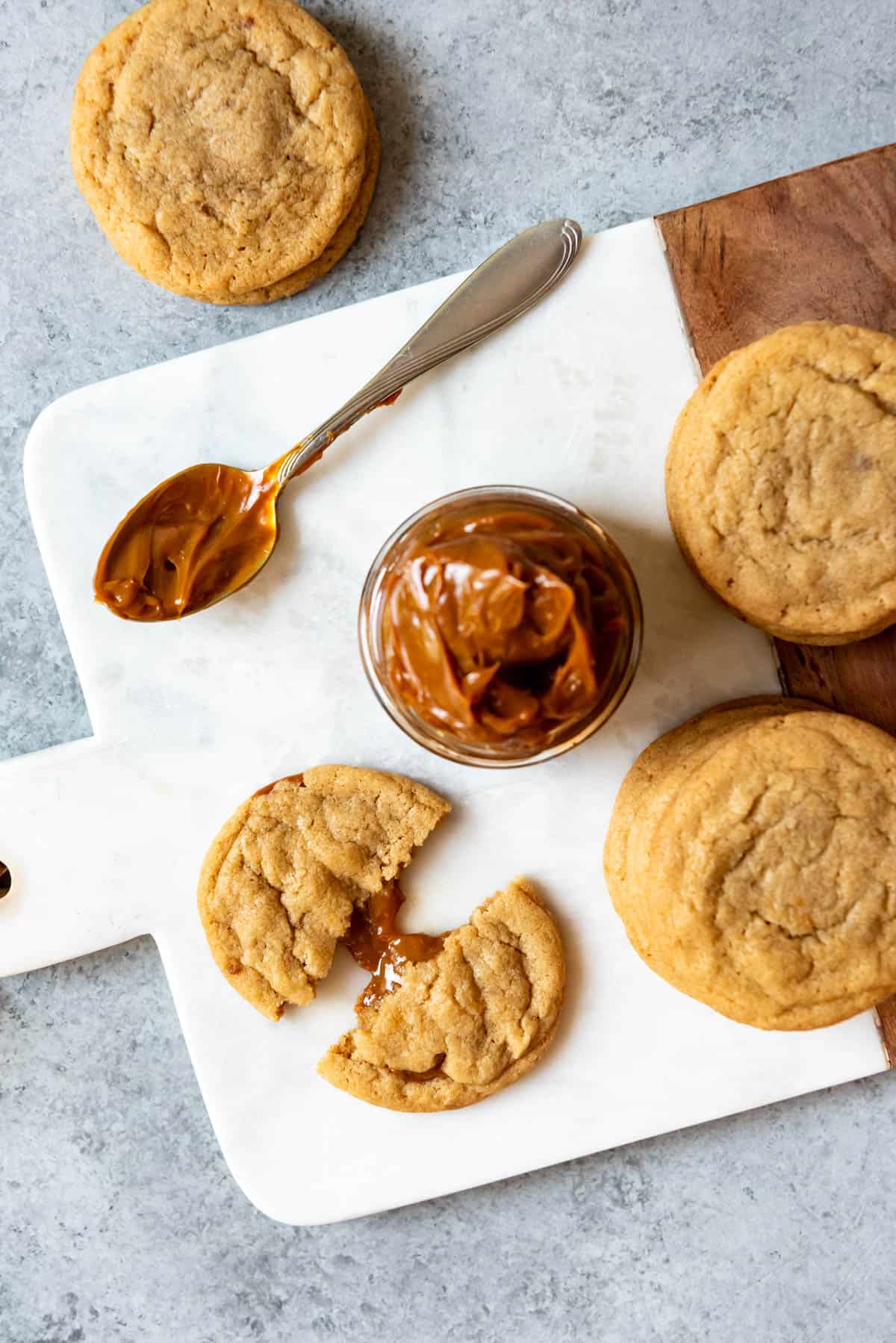 An overhead image of dulce de leche stuffed cookies next to a jar of dulce de leche.