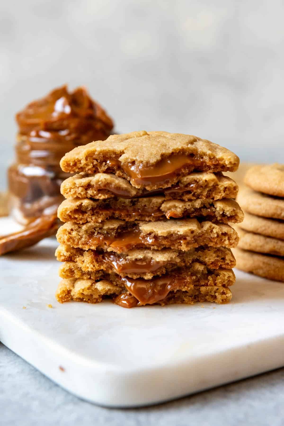 An image of cookies stuffed with dulce de leches stacked on top of each other with dulce de leche oozing out.