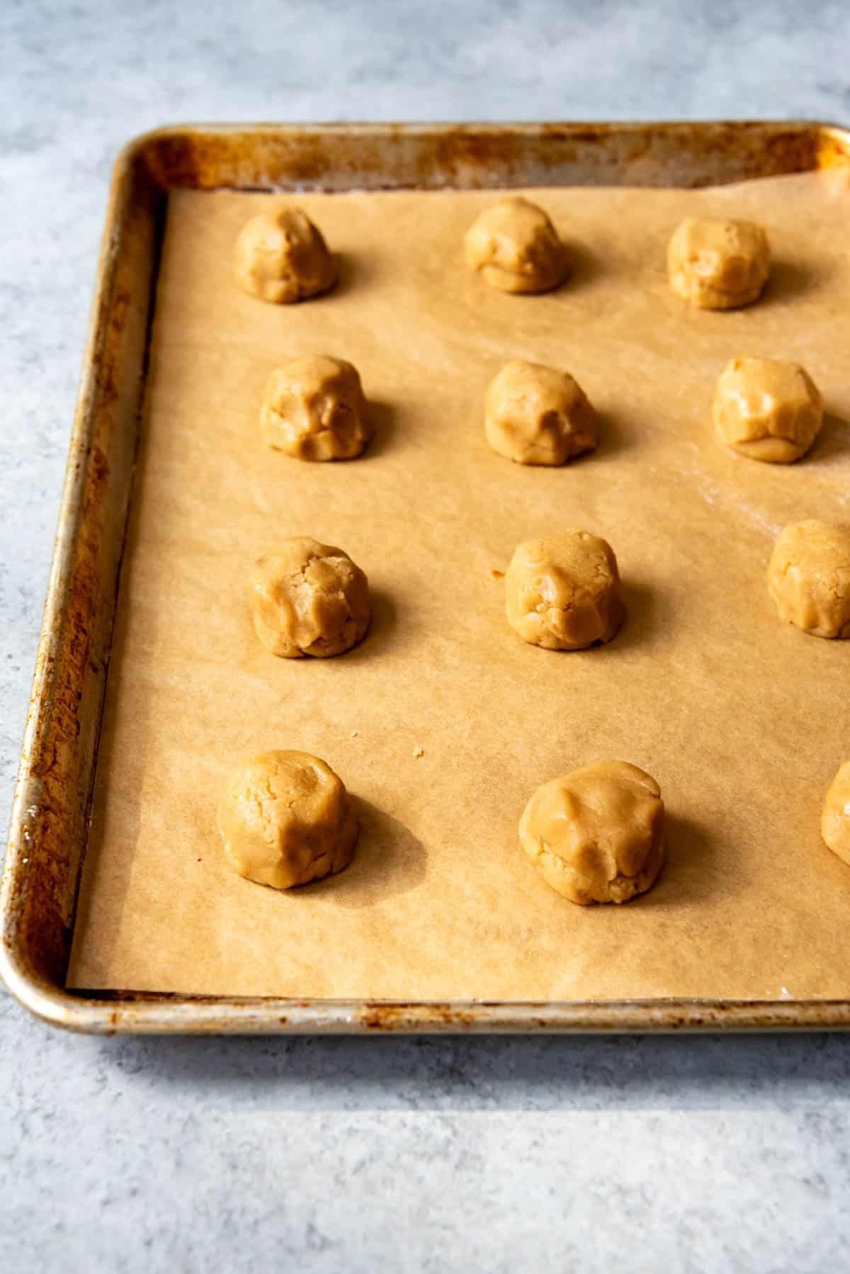 Balls of brown sugar cookie dough on a baking sheet.