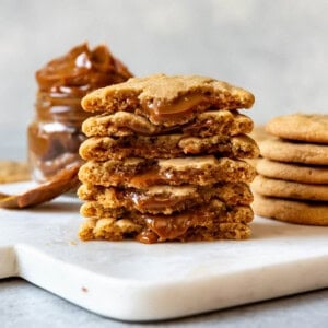 An image of cookies stuffed with dulce de leches stacked on top of each other with dulce de leche oozing out.