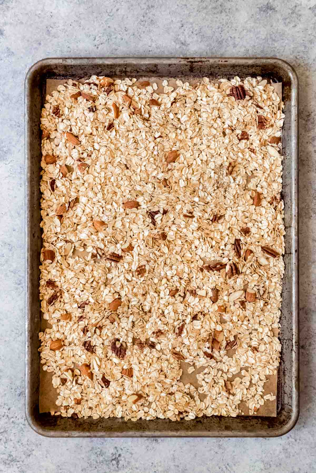 An image of a baking sheet with toasted oats and nuts for making chewy granola bars.