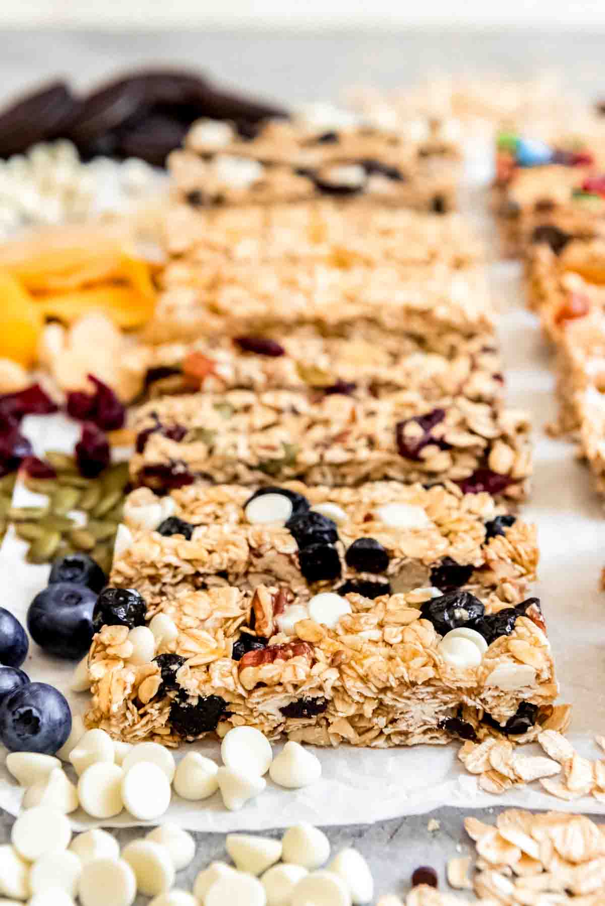 An side image of lemon blueberry white chocolate granola bars showcasing the tightly packed oats sweetened with honey and brown sugar and mixed with lemon zest, dried blueberries, pecans, and white chocolate chips.