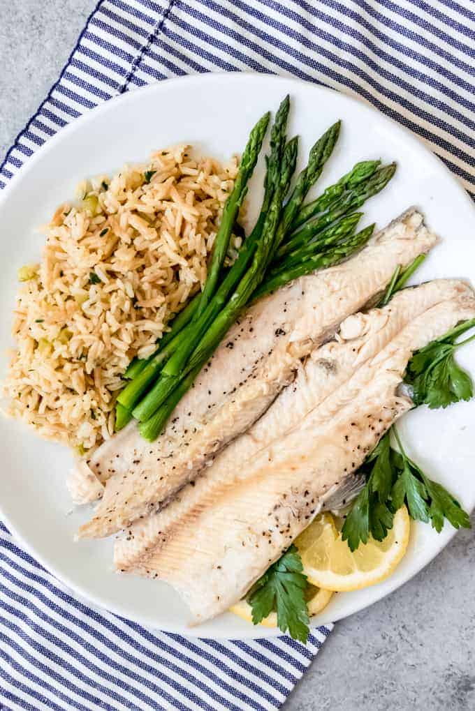 An image of a plate of baked trout filet with asparagus and rice pilaf.