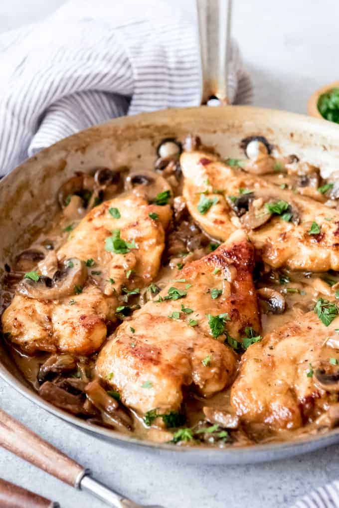 An image of pan fried chicken breasts in a pan with a creamy marsala wine sauce and mushrooms.
