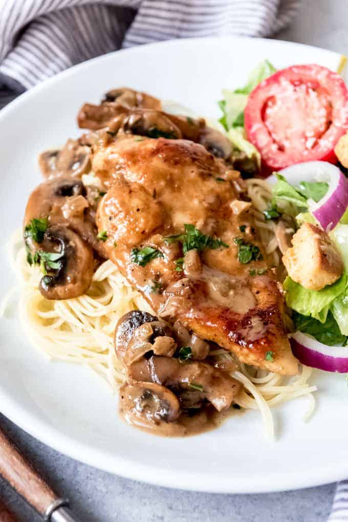 An image of a serving of chicken marsala over angel hair pasta.