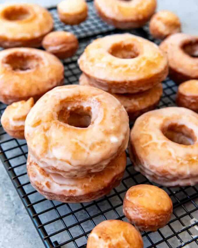 An image of glazed cake doughnuts on a wire cooling rack.