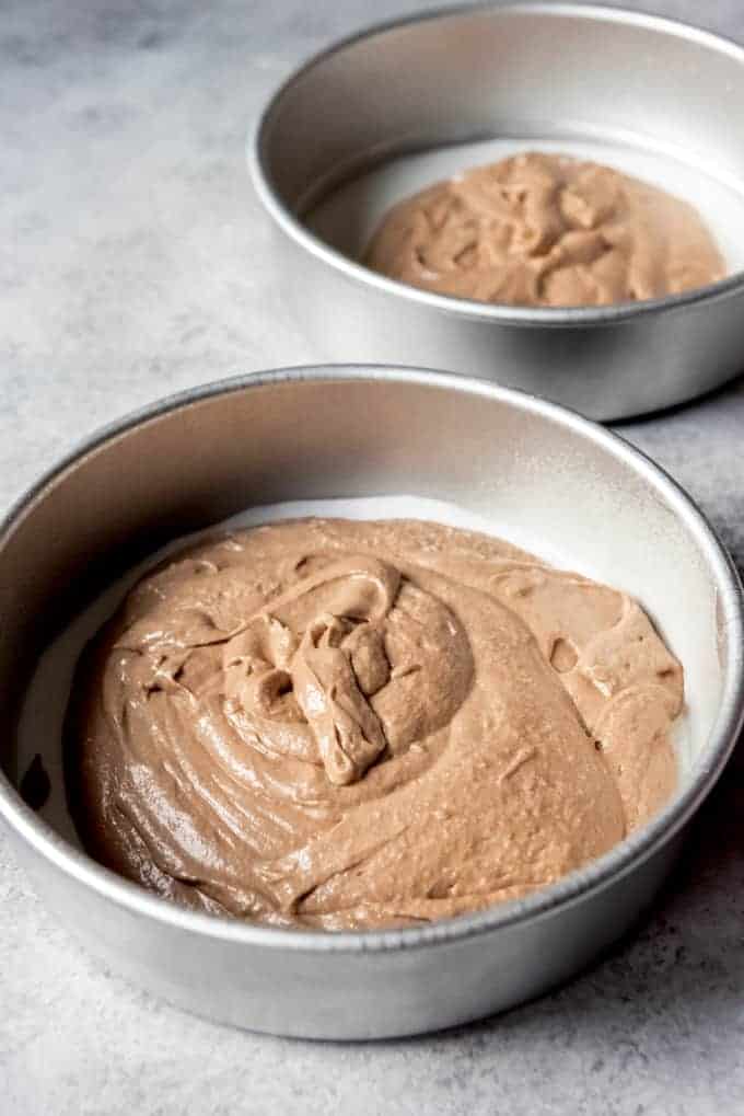 An image of chocolate cake batter in 9-inch round cake pans.