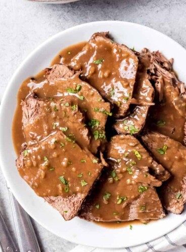 An image of German sauerbraten sliced on a plate with gravy on top.