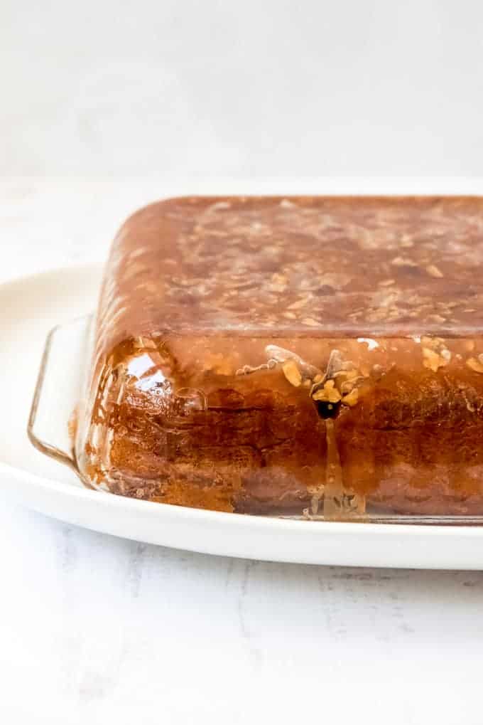 An inverted glass baking dish with caramel pecan sticky buns inside.