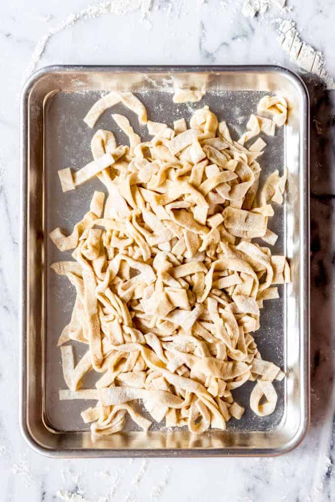 An image of homemade egg noodles on a baking sheet.