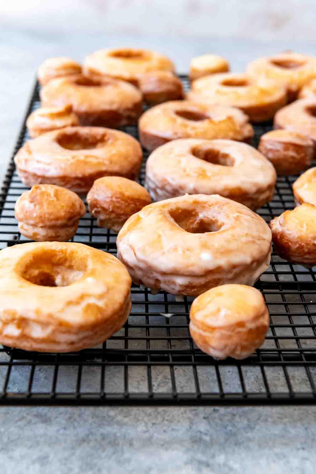 An image of glazed cake doughnuts on a wire cooling rack.