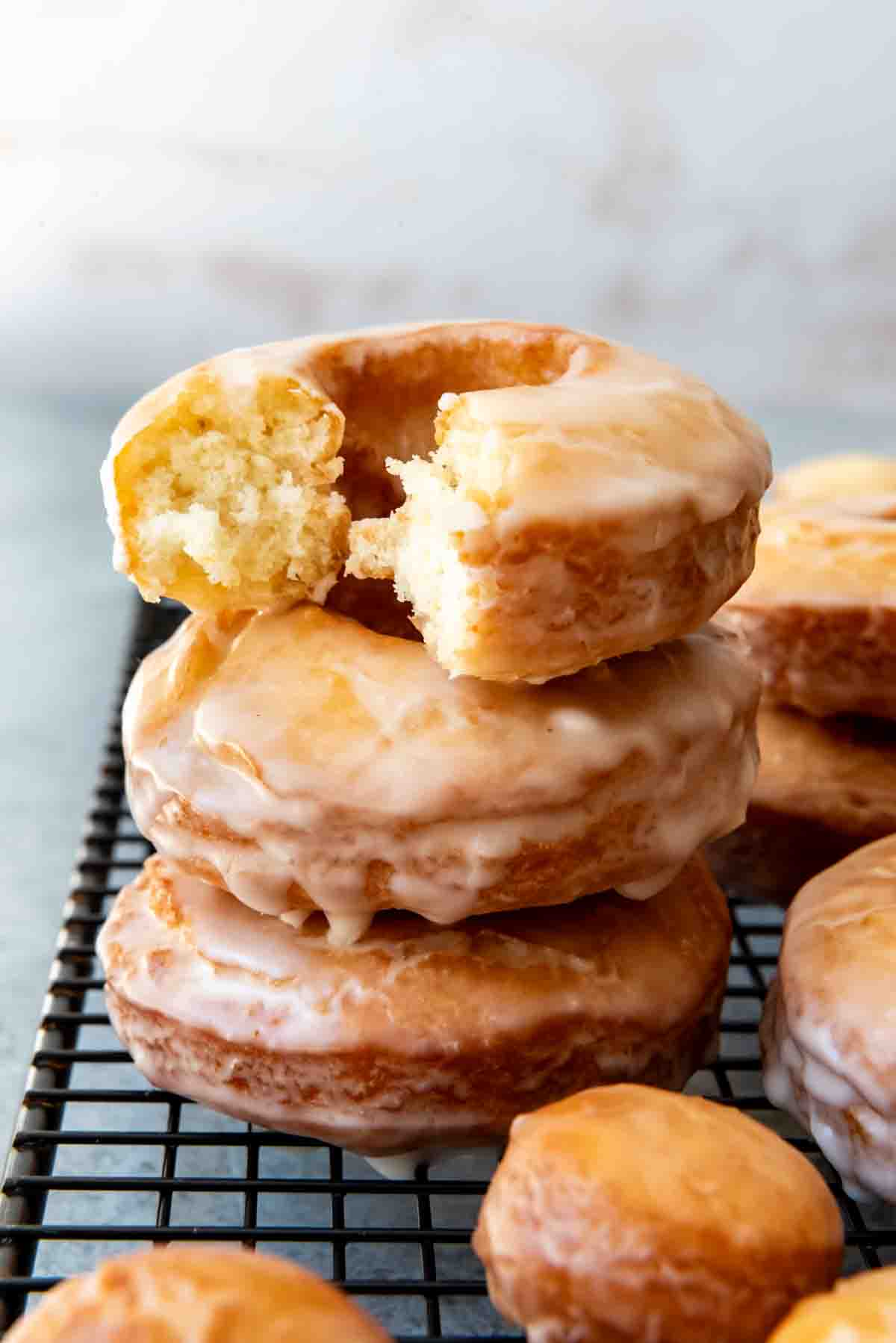 An image of glazed cake doughnuts staked on top of each other.