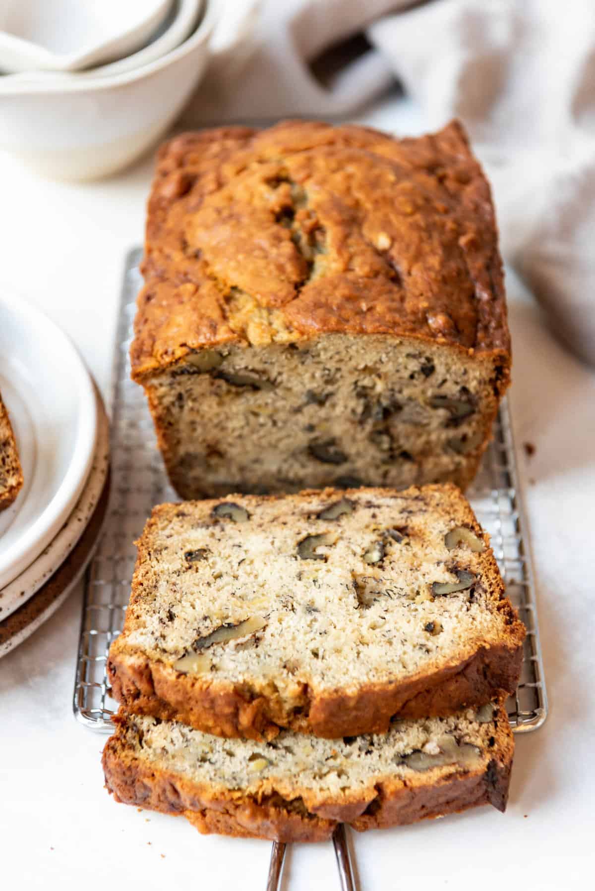 Two slices of banana bread in front of the rest of the loaf.