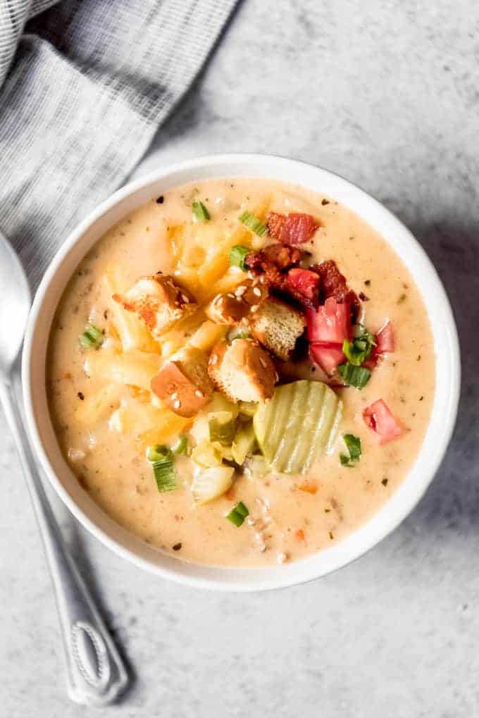 An image of a bowl of creamy Cheeseburger Soup topped with lots of garnishes.